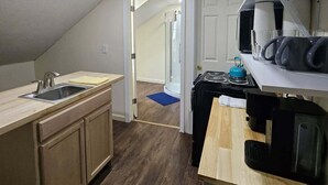 A compact kitchen with a sink, stove, and kettle, leading to a bathroom with a shower. - Nice apartment near Whole Foods, Brown University, Miriam Hospital, Downtown (Providence)