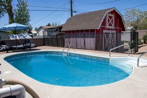 A swimming pool with a red barn in the background.