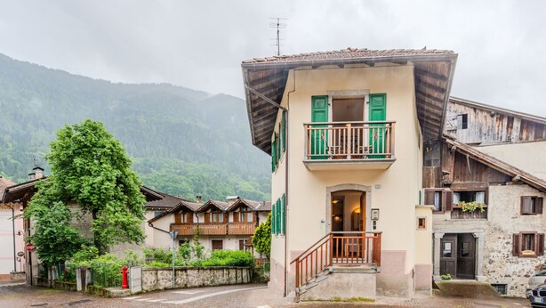 Un chalet traditionnel doté d’un balcon, situé dans une rue pavée, avec une vue imprenable sur les montagnes.