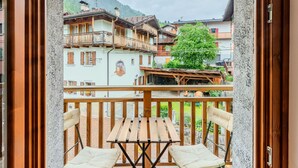 Un balcon agrémenté de meubles en bois, une vue sur des bâtiments traditionnels et une montagne en arrière-plan.