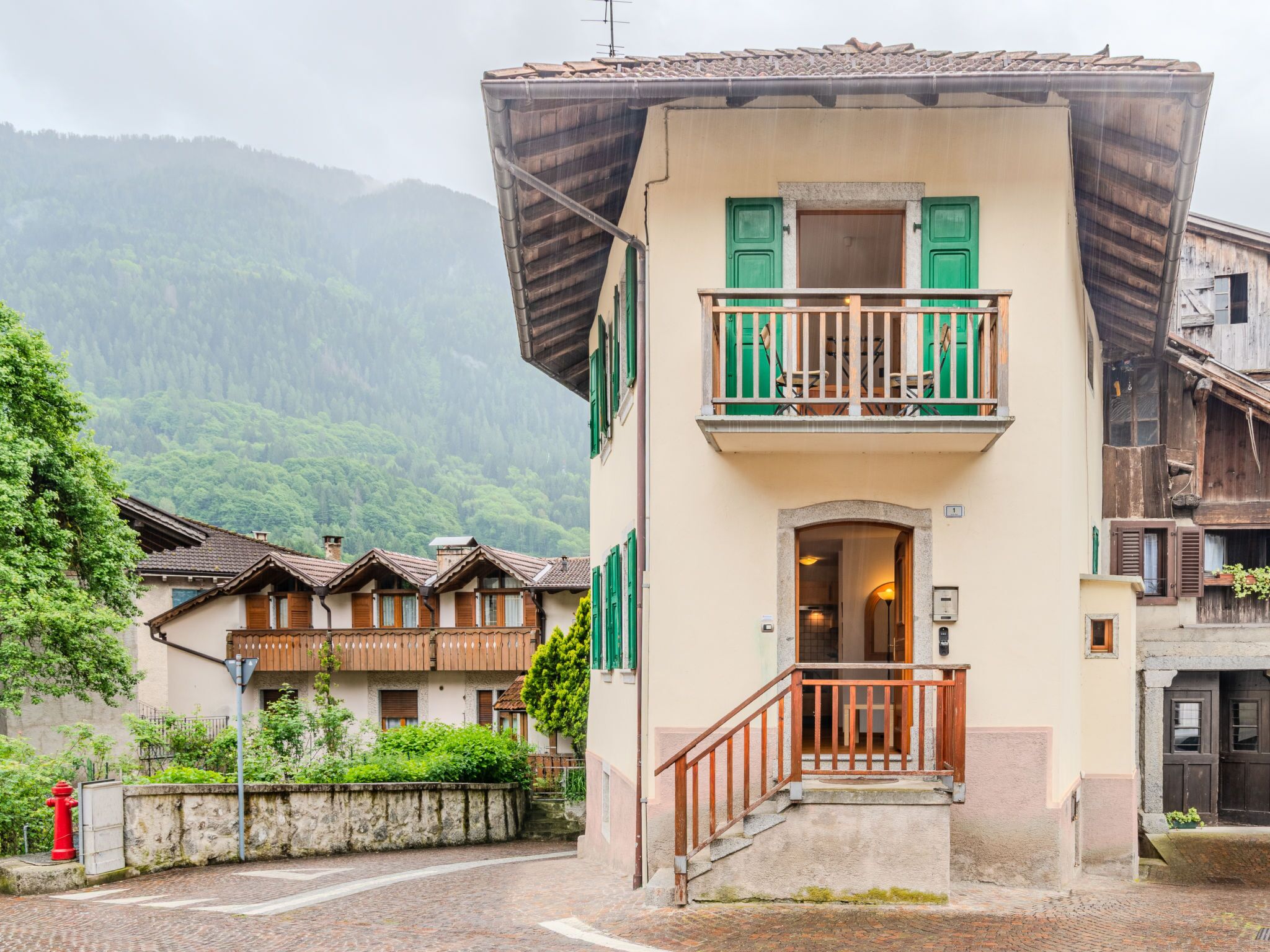 Ein traditionelles Gebäude mit Balkon, Steinmauer und rotem Hydrant.