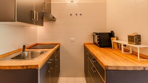 Eine kleine Küche mit Spüle aus Edelstahl, Holz Arbeitsplatte und modernen Schränken.