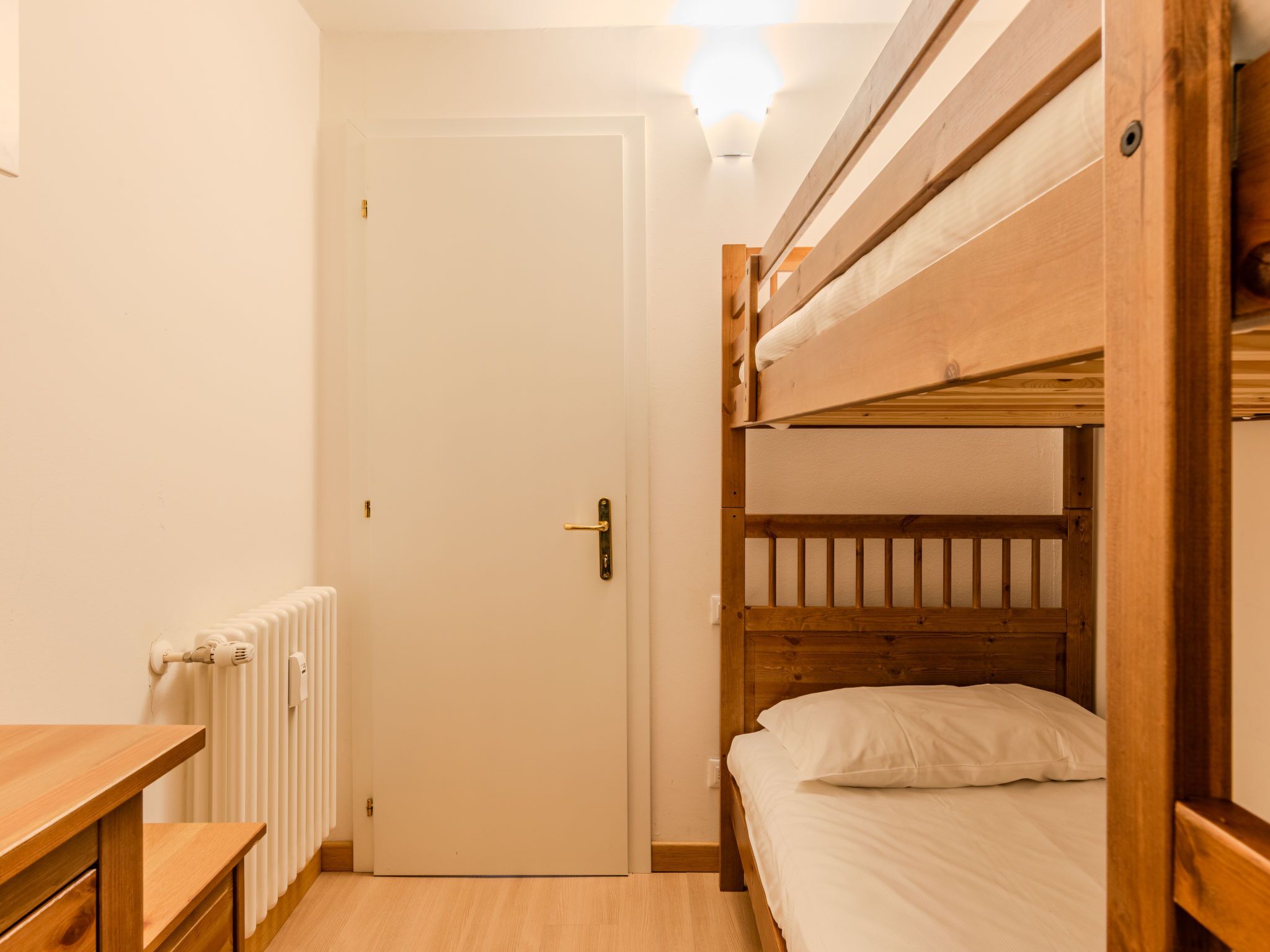 Dormitorio con literas, un escritorio de madera y un radiador.