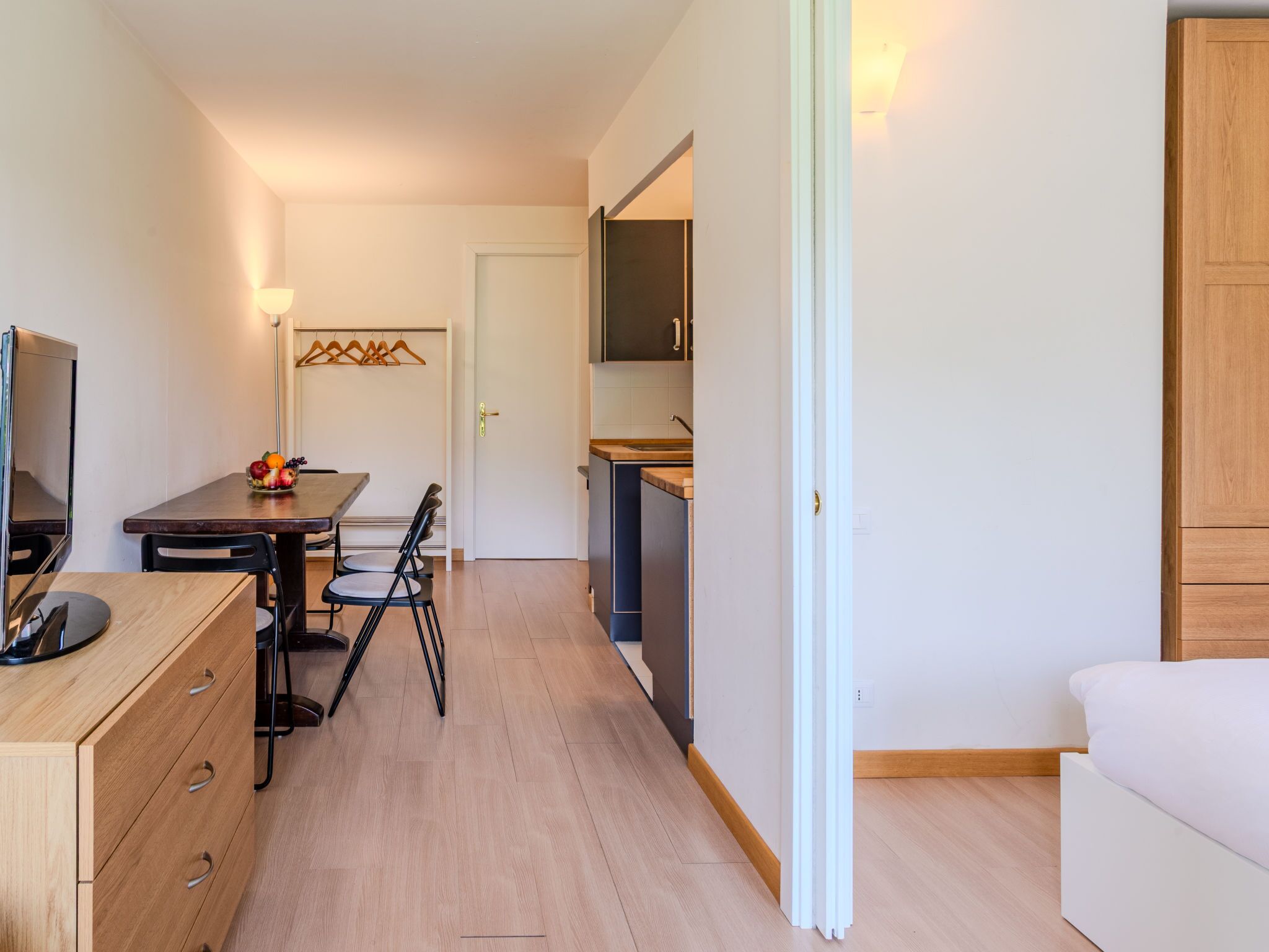 A compact living space with a dining area, kitchenette, and a bed.