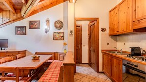 Una cocina acogedora con armarios de madera, una mesa de comedor con bancos y un suelo de baldosas.