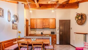 Una cocina acogedora con armarios de madera, una mesa de comedor con sillas a cuadros y un sofá rojo.