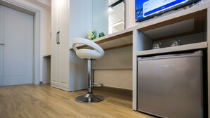 A modern kitchen with a stainless steel refrigerator, a white bar stool, and a television mounted above the counter. - Grandstay Beach Room 01 (Durrës)