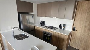 Een moderne keuken met een centraal eiland, roestvrijstalen apparatuur en houten keukenkastjes.