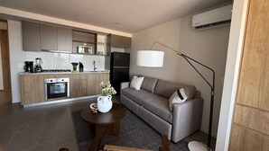 Ein stilvoller Wohnraum mit Küche, grauem Sofa, Couchtisch und einer Stehlampe.