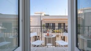 A balcony with white chairs and a small table, overlooking a building with tiled walls and a clear sky. - Apartment 'Lemos' with Private Terrace, Wi-Fi and Air Conditioning (Triggianello)