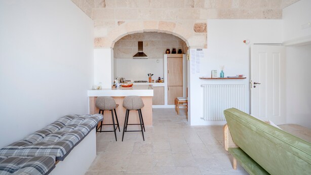 A kitchen with a stone archway, a bench, and a green sofa. - Apartment 'Lemos' with Private Terrace, Wi-Fi and Air Conditioning (Triggianello)