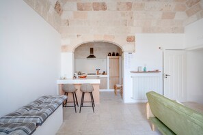 A kitchen with a stone archway, a bench, and a green sofa. - Apartment 'Lemos' with Private Terrace, Wi-Fi and Air Conditioning (Triggianello)