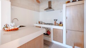 A kitchen with a brick wall, white cabinetry, a gas stove, and a stainless steel sink. - Apartment 'Lemos' with Private Terrace, Wi-Fi and Air Conditioning (Triggianello)