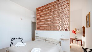 A bedroom with a bed, a bedside table, a chair, and a decorative wall panel. - Apartment 'Lemos' with Private Terrace, Wi-Fi and Air Conditioning (Triggianello)