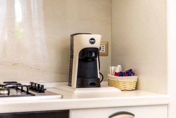 Una cafetera sobre una encimera de cocina con un atril de pañuelos de papel y un enchufe al fondo.