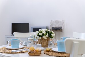 Une table de petit-déjeuner avec un set de table en fibres tressées, un panier de fleurs blanches et une tasse bleue.