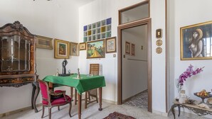 A dining area with a green tablecloth, wooden chairs, a decorative cabinet, and framed artwork on the walls. - Holiday Home 'Al Castello' with Private Terrace, Wi-Fi and Air Conditioning (Ficarazzi)