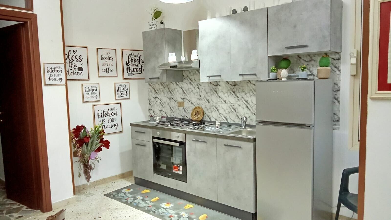 Een keuken met een marmeren spatwand, roestvrijstalen apparatuur en decoratieve wandborden.