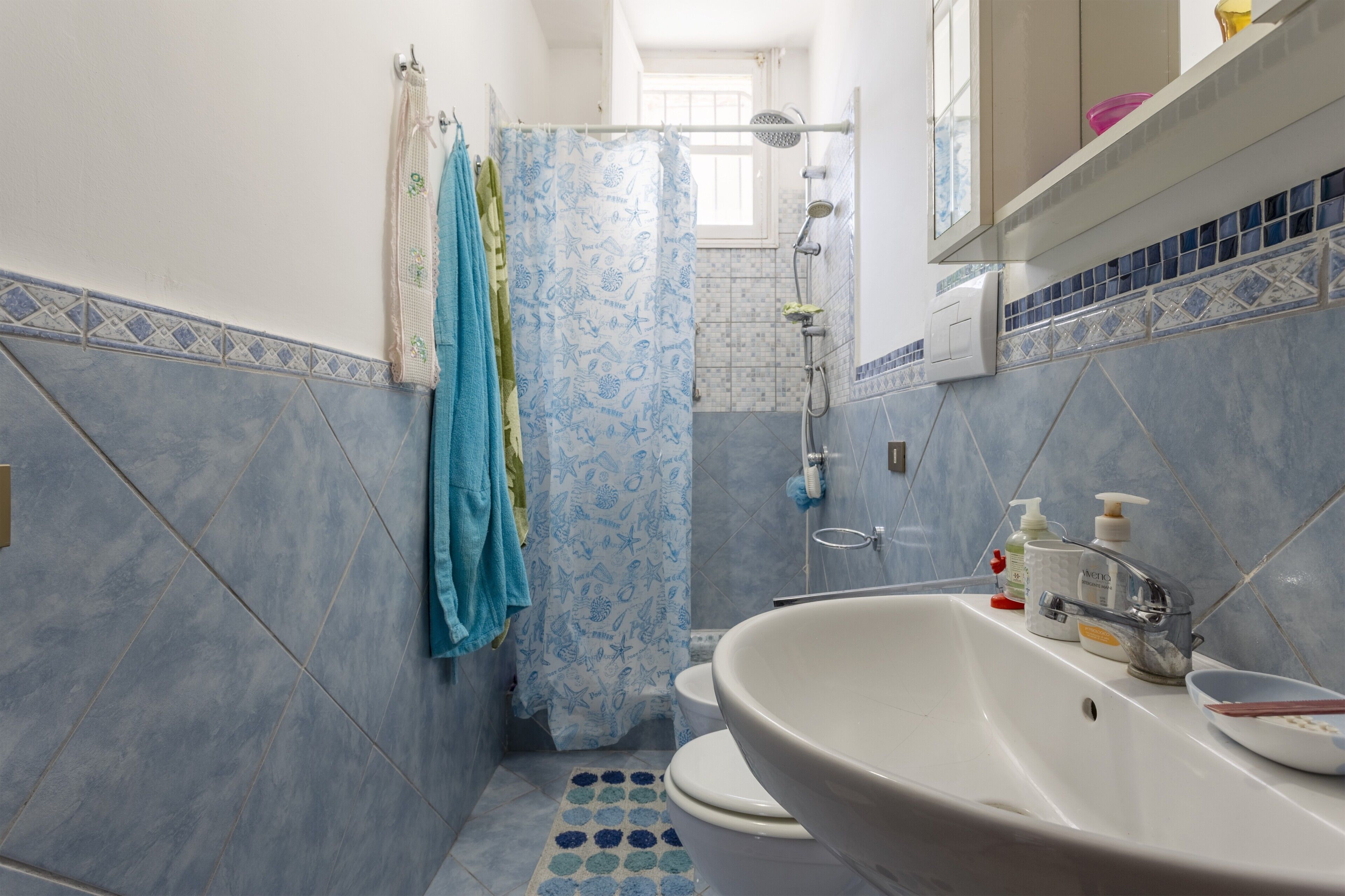Une salle de bain avec une baignoire, des toilettes, une douche et un sol carrelé avec un motif bleu.