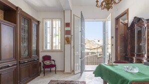 A room with a wooden cabinet, a red chair, a green table, and a patterned rug. - Holiday Home 'Al Castello' with Private Terrace, Wi-Fi and Air Conditioning (Ficarazzi)