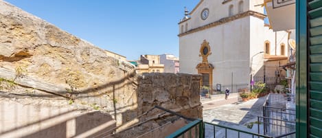 A stone wall, a church with a clock, and a green railing.