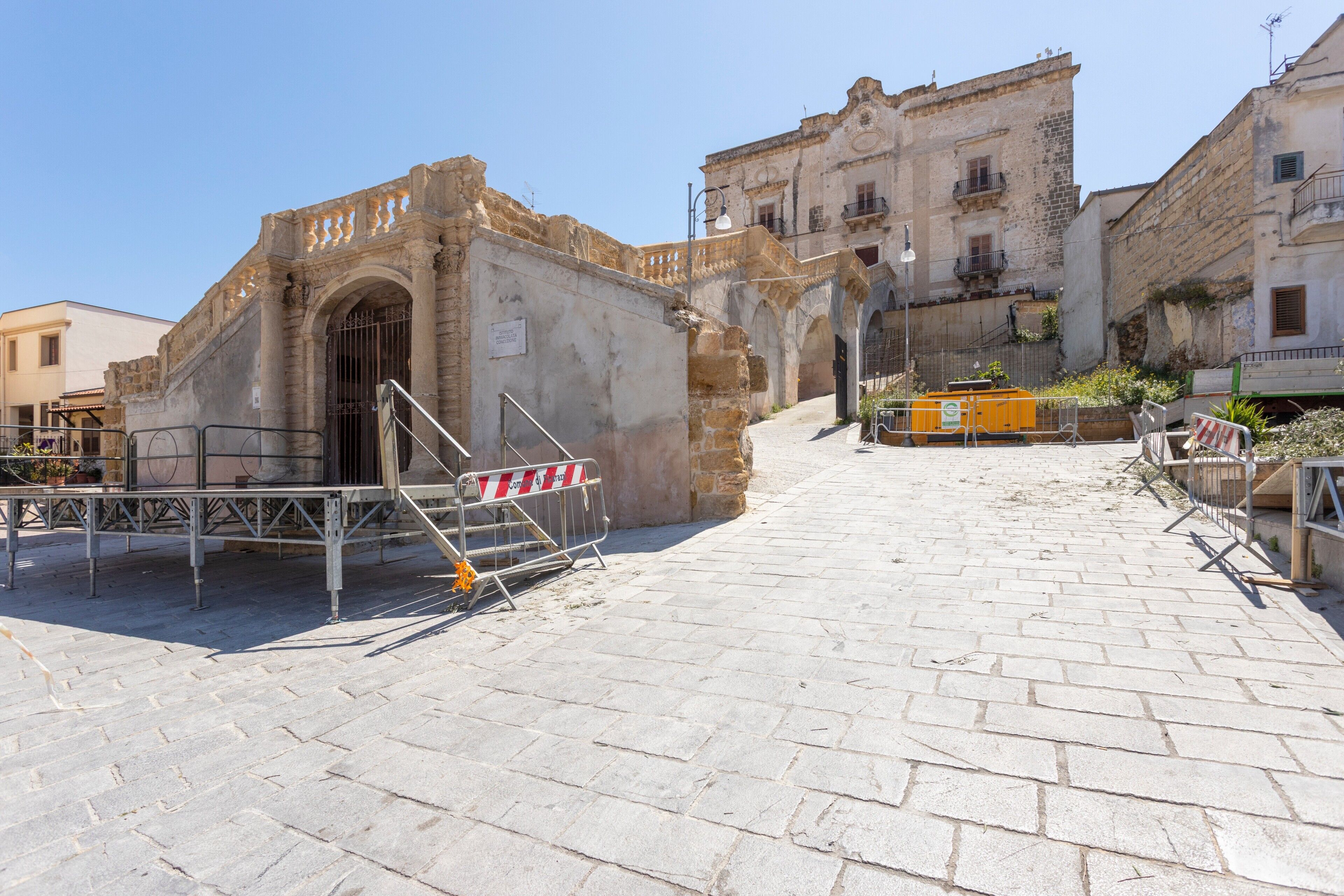 A historic building with a stone facade, a gated entrance, and a paved courtyard.