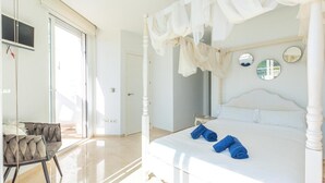 A bedroom with a four-poster bed, a chair, and a large window.