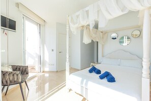 Quarto com cama de dossel, uma cadeira e uma janela grande.