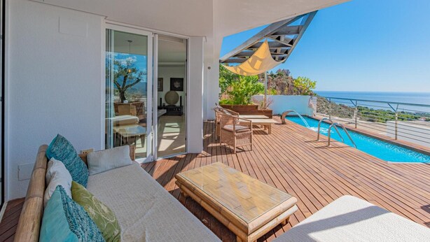 A balcony with a pool, outdoor furniture, and a view of the ocean.