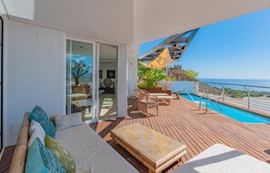 Een balkon met een zwembad, buitenmeubilair en uitzicht op de oceaan.