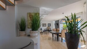 A modern interior with a dining area, potted plants, and a staircase.