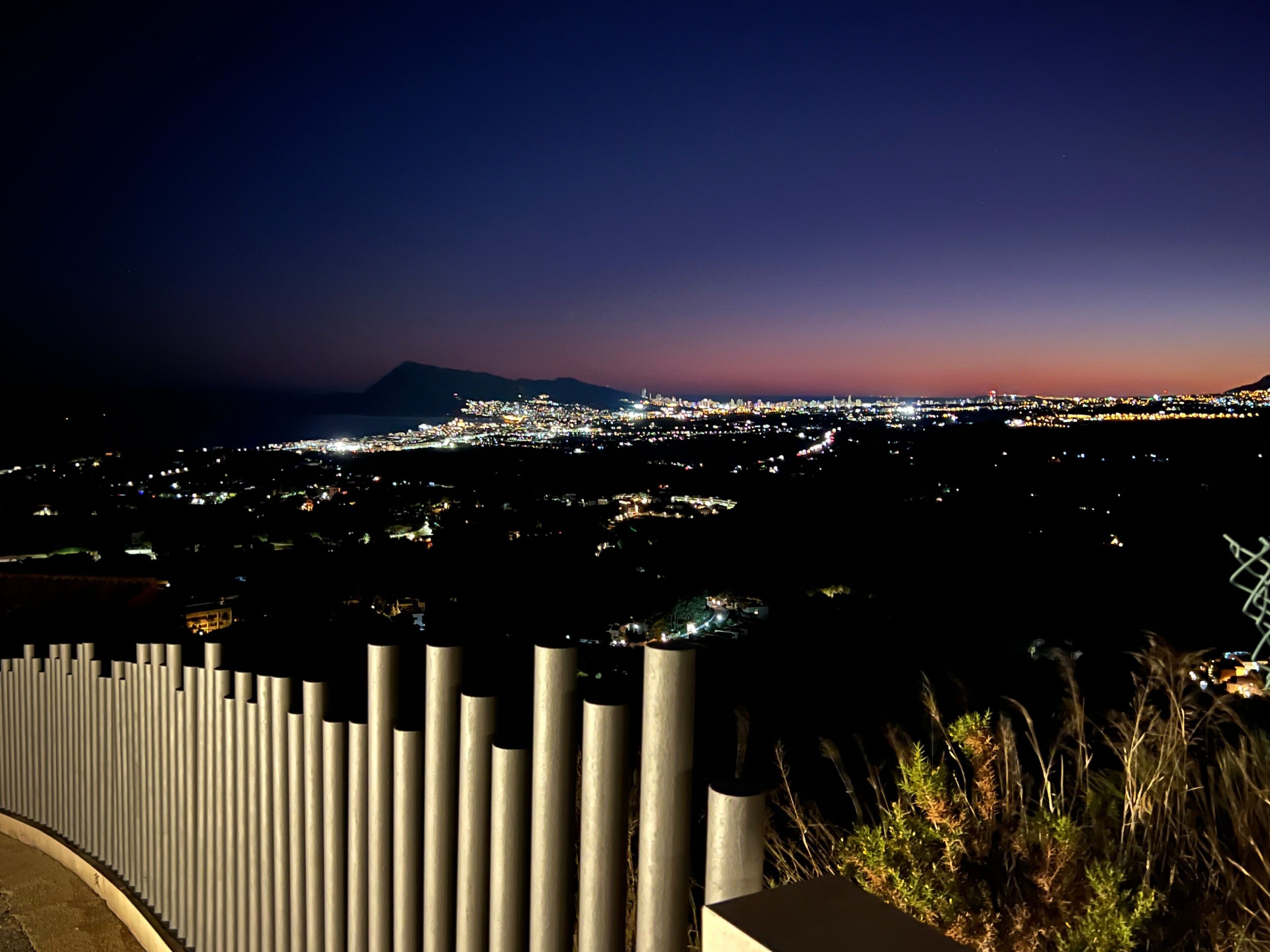 A nighttime cityscape with a mountain in the background.