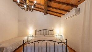 Een slaapkamer met een bed, nachtkastjes, een kroonluchter en een airconditioning.