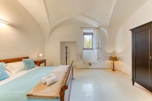 A bedroom with a bed, a wardrobe, a window, and a lamp.