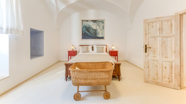 A bedroom with a bed, a wicker basket, a painting, and a wooden door. - Room 'Serena - 3' with Private Terrace, Wi-Fi and Air Conditioning (Presicce)