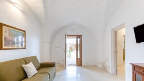 Un couloir avec un canapé, un tableau et une porte donnant sur un espace extérieur.