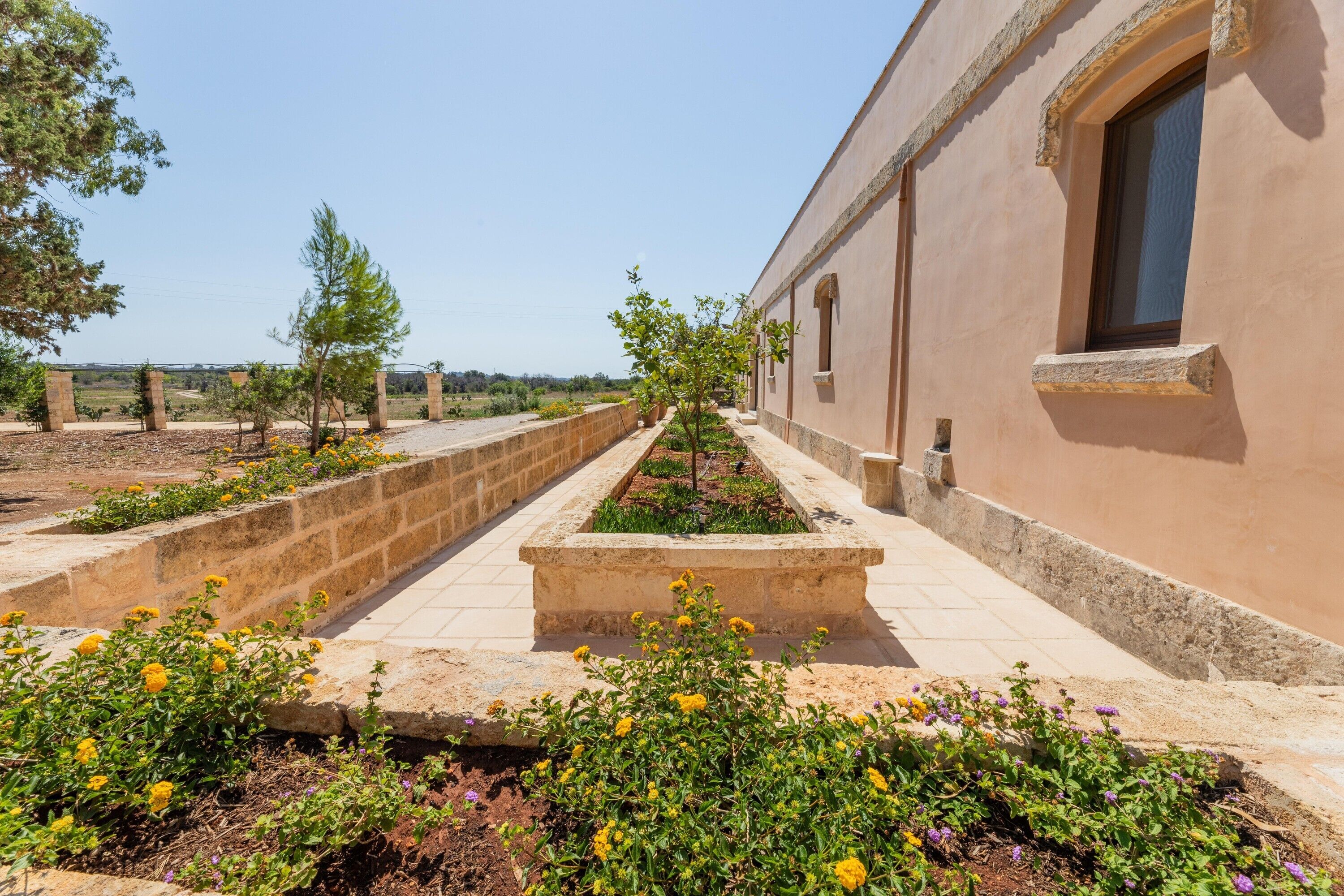 Un sendero que conduce a un edificio con una pared de piedra y una ventana.