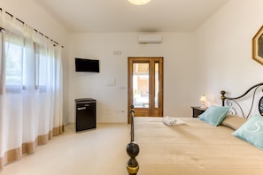 A bedroom with a bed, a TV, a door, and a small table with a lamp. - Room 'Sara - 6' with Private Terrace, Wi-Fi and Air Conditioning (Presicce)