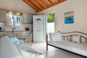Une pièce comprenant un lit, un canapé, une table à manger avec des chaises, un coin cuisine et une porte donnant sur l’extérieur.