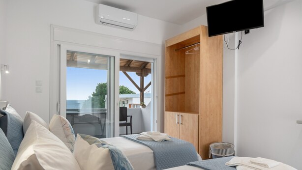 Ein Schlafzimmer mit Bett, Fernseher, Holzschrank und Blick durch eine Glastür.