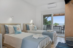 A hotel room with two beds, a balcony, and a view of the sea.