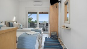 Ein Schlafzimmer mit zwei Betten, einem Fernseher, einem Schreibtisch und Blick ins Freie.