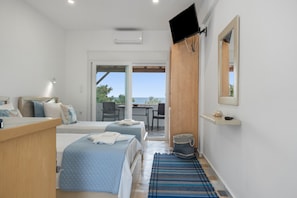 A bedroom with two beds, a TV, a desk, and a view of the outdoors.