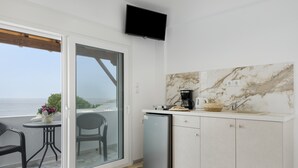 A compact kitchen with a marble backsplash, a small refrigerator, and a dining area with a table and chairs. - Apartment 'Double Studio No 9' with Balcony and Wi-Fi (Kalymnos)