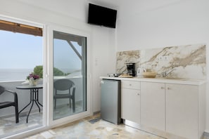 A compact kitchen with a marble backsplash, a small refrigerator, and a dining area with a table and chairs.