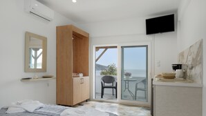 A bedroom with a bed, a wooden wardrobe, a television, and a balcony with a chair. - Apartment 'Double Studio No 9' with Balcony and Wi-Fi (Kalymnos)