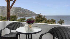 A balcony with a table and chairs, a vase of flowers, and a view of the sea and mountains. - Apartment 'Double Studio No 9' with Balcony and Wi-Fi (Kalymnos)