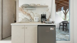 Une cuisine compacte dotée d’un plan de travail en marbre, d’une machine à café et d’un réfrigérateur.
