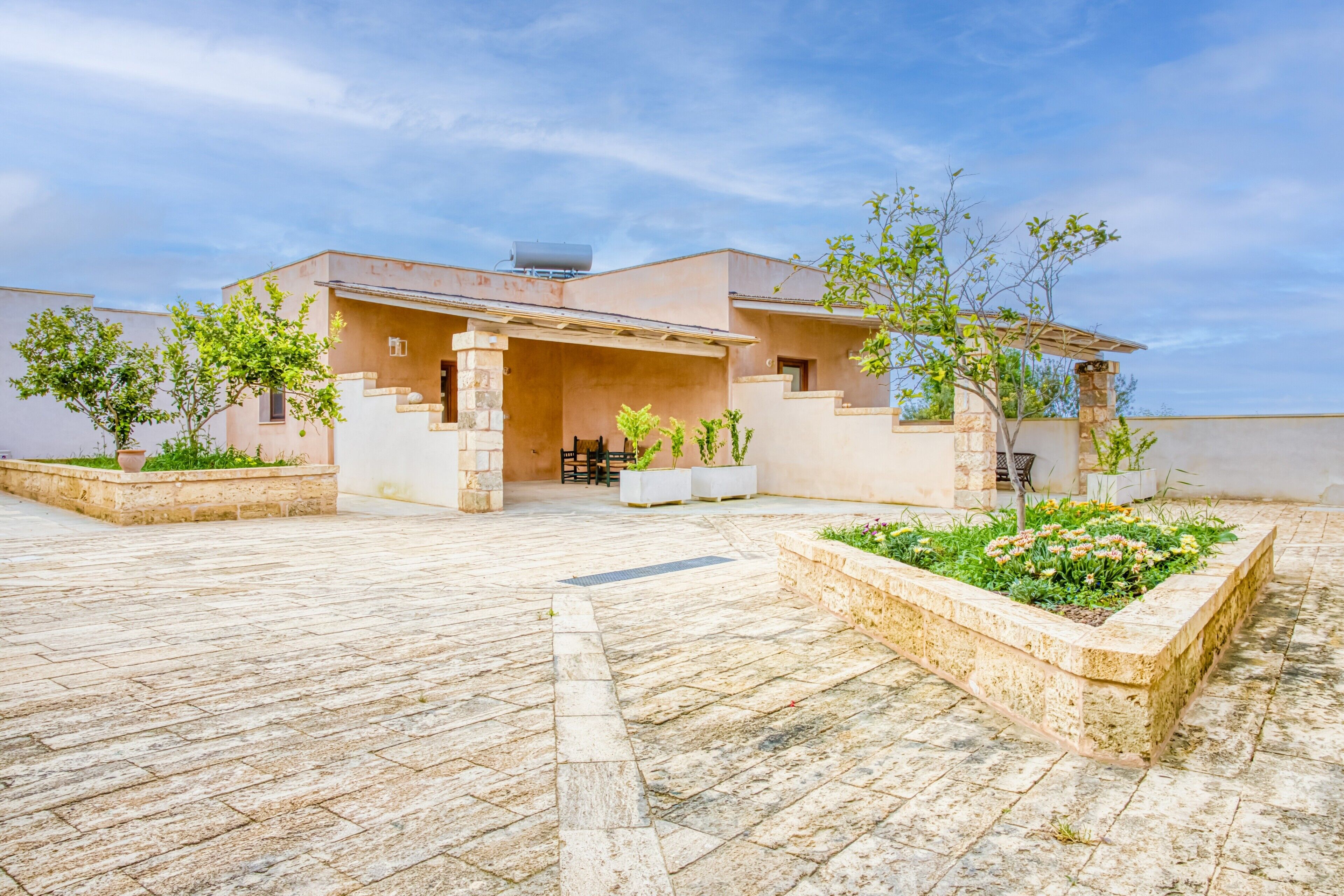 A modern house with a stone courtyard, a covered porch, and potted plants.