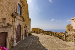 A stone building with arched doorways and a courtyard with a chalk drawing.